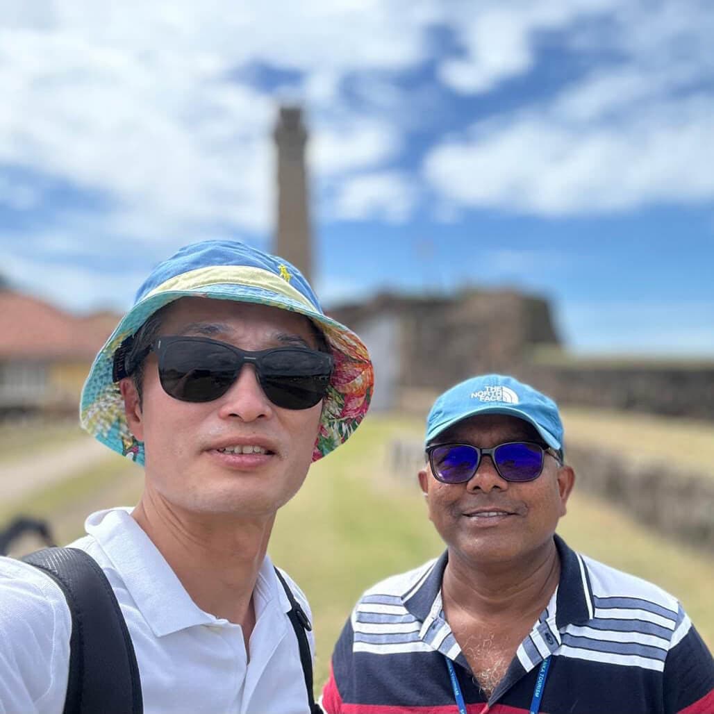 The white lighthouse standing tall on the green ramparts of Galle Fort overlooking the ocean
